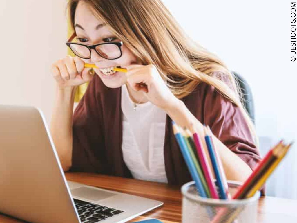 a woman at a desk gnaws a pencil
