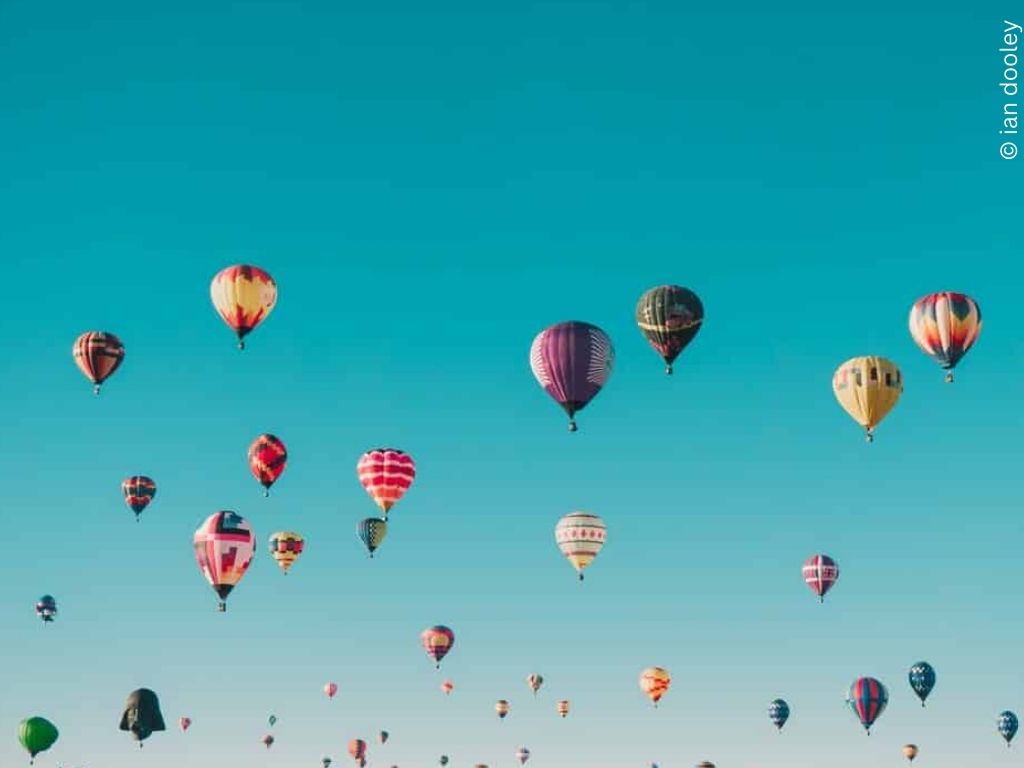 Lots of hot air balloons against a blue sky