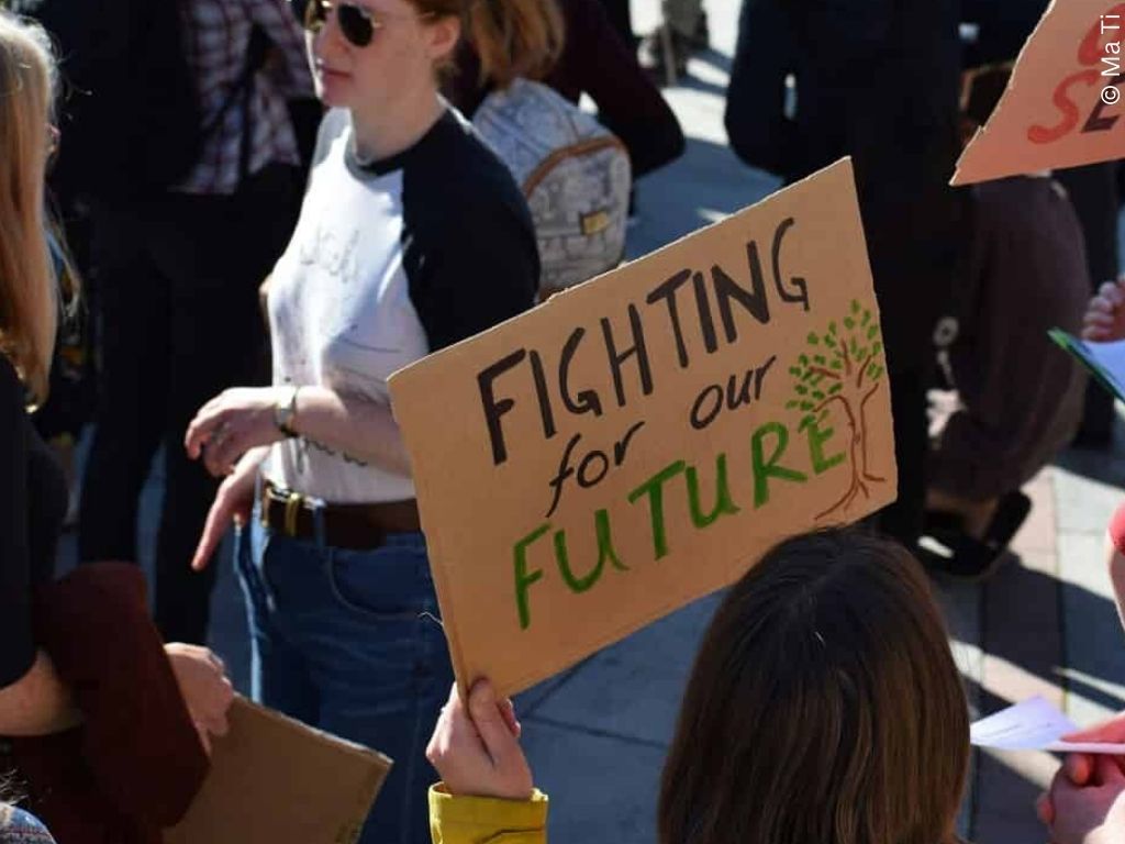 A child holds a banner which reads 'fighting for our future'