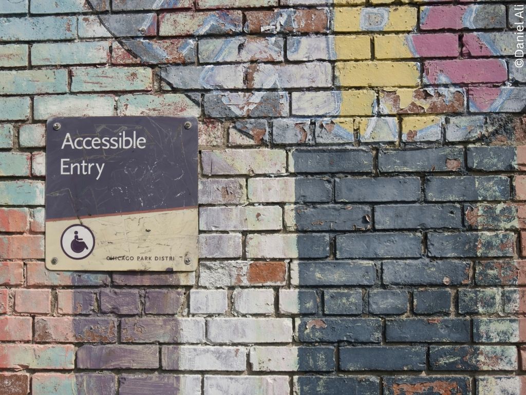 A graffitied wall with a sign reading 'accessible entry'.