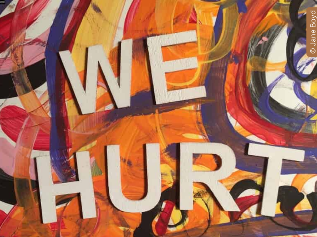 A graffiti wall with 'we hurt' written across it.