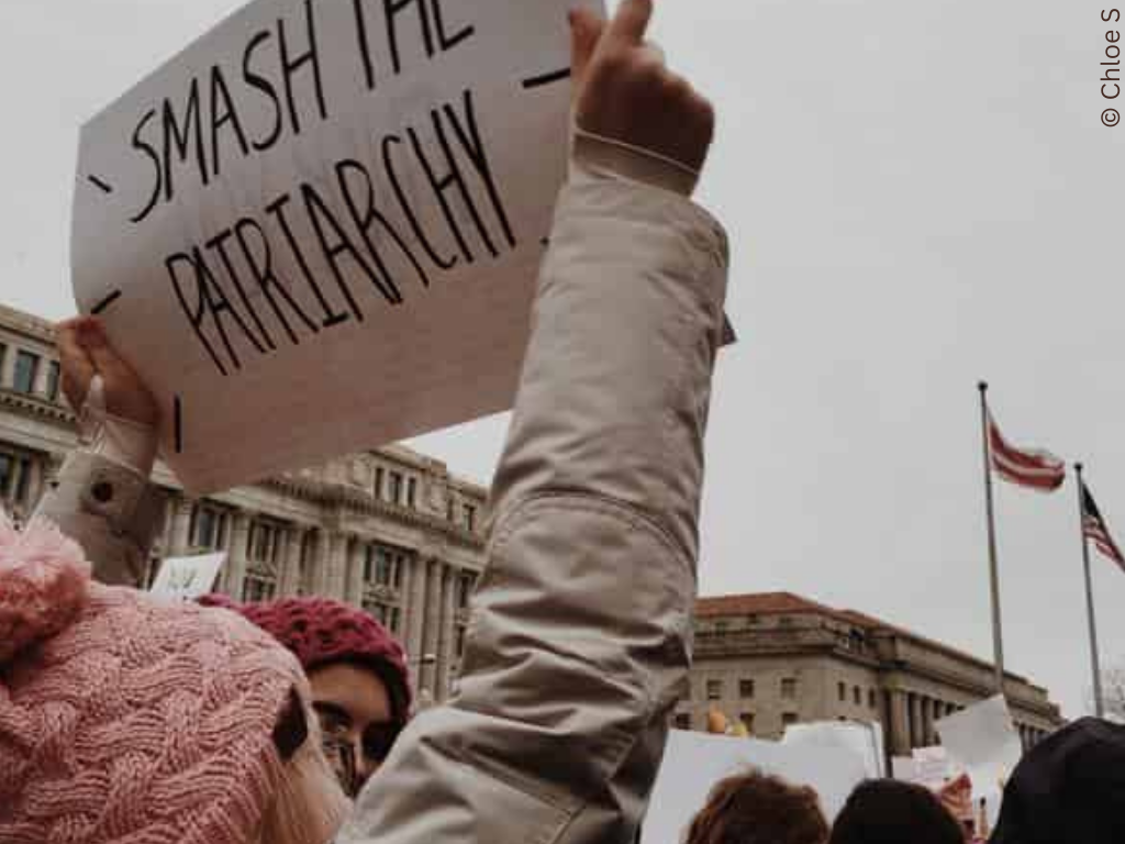 Small child holds up a sign. The sign reads 'Smash the Patriarchy'